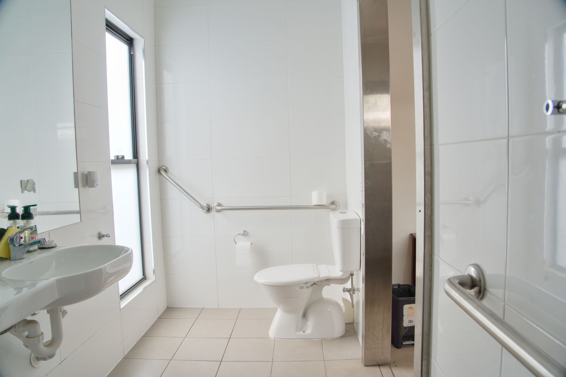 A brightly lit living and dining area with a blue couch, a dark brown sofa, a round dining table, and a TV console.