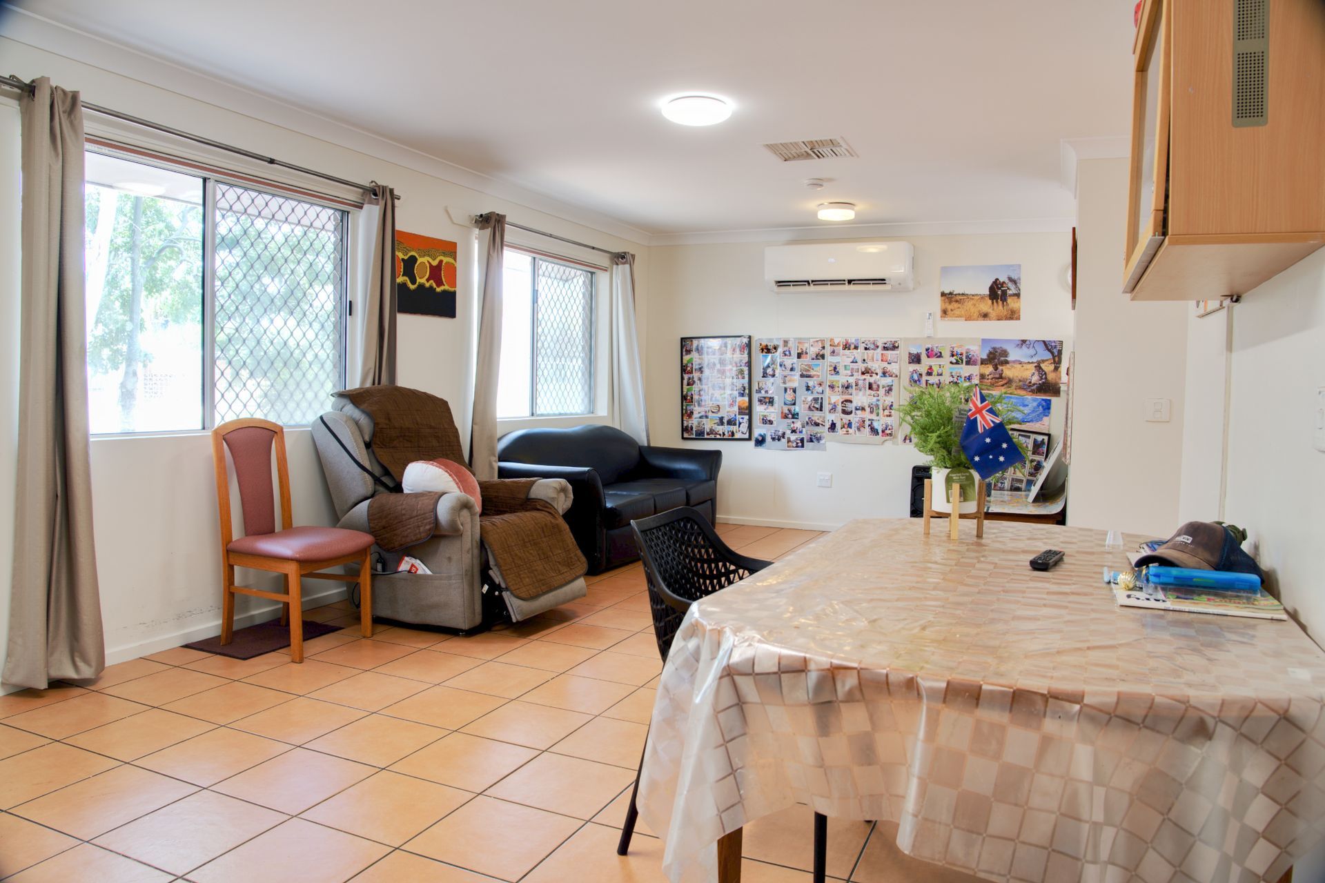 A single-story brick house with a white roof, a side carport with a silver SUV, and an outdoor cooling unit near the front.