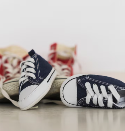 Dos pares de zapatillas deportivas para bebé, unas azul marino y otras rojas, sobre una superficie neutra.