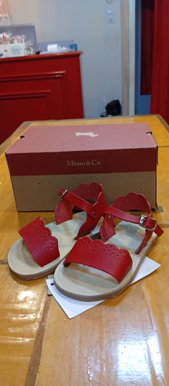 Sandalias rojas y una caja sobre una mesa de madera.