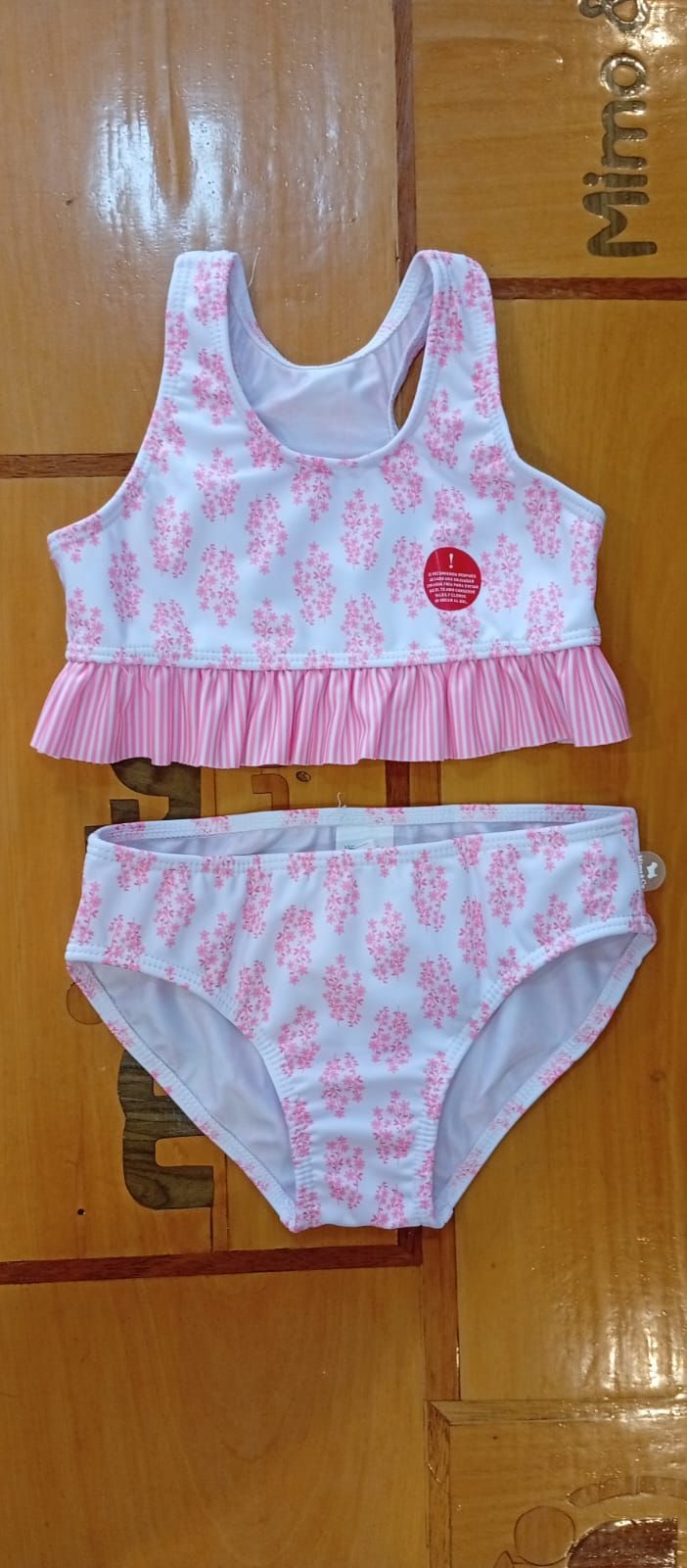Conjunto de bañador de dos piezas con estampado floral rosa para niña. Volante rosa claro en el bajo del top.