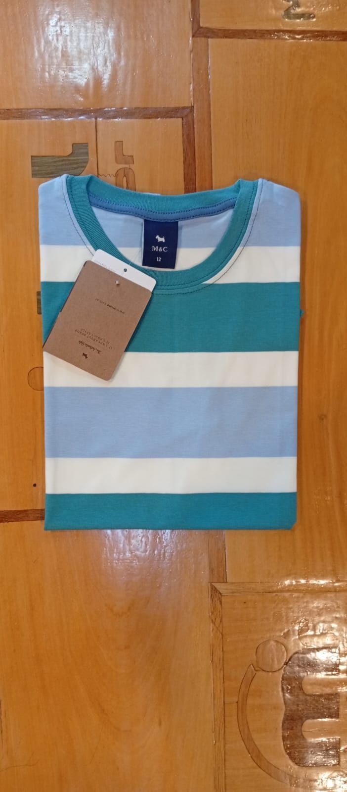 Una camiseta de rayas doblada sobre una superficie de madera con una etiqueta de precio.
