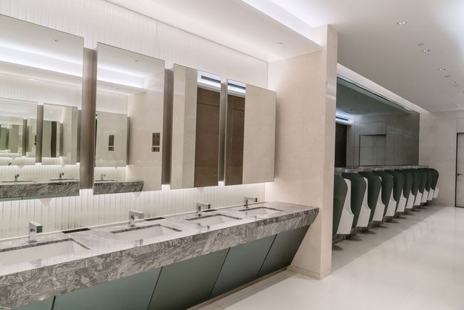 Des toilettes publiques avec beaucoup de lavabos et de miroirs.