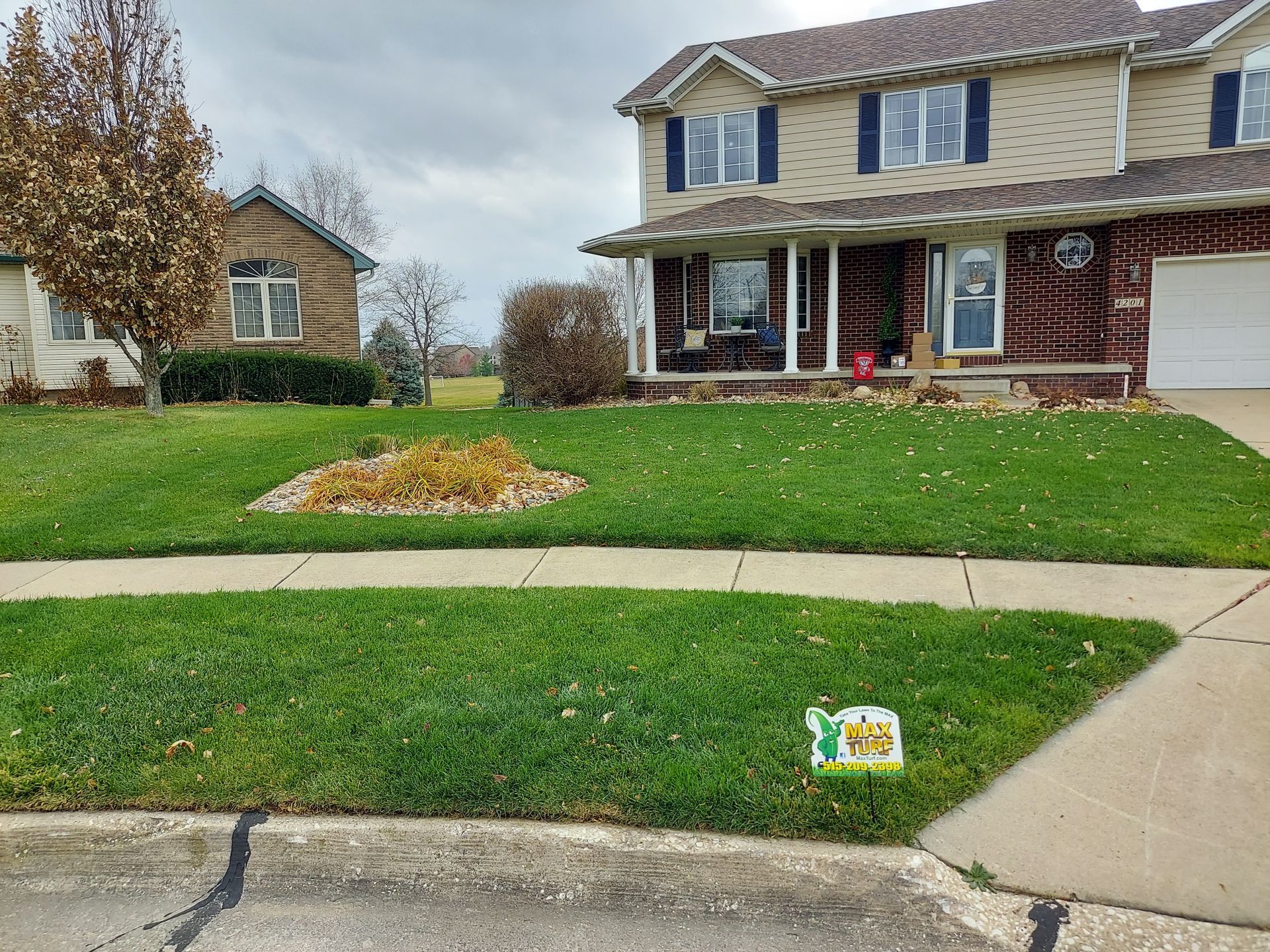 A large house with a lush green lawn and a sidewalk in front of it.