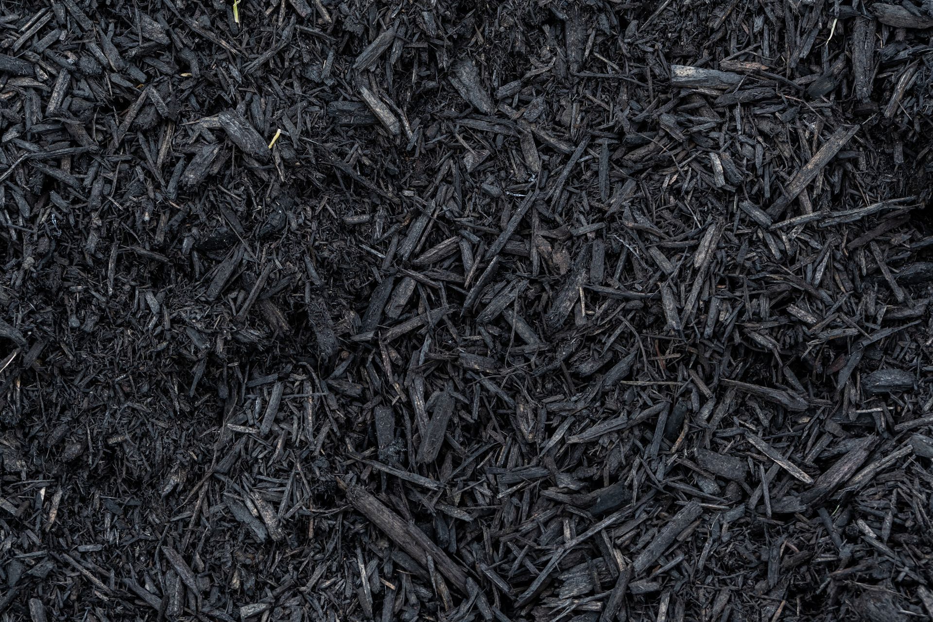 A pile of black mulch is sitting on the ground.