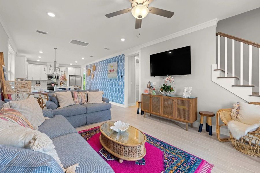 Living room with blue sofa, pink rug, TV, and rattan decor.