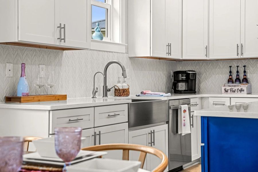 White kitchen with stainless steel sink, cabinets, and a blue island.