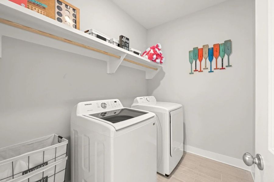 Laundry room with white washer and dryer, shelves, and colorful wall art.