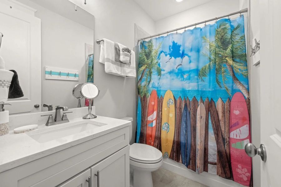 Coastal bathroom with a surfboard shower curtain.