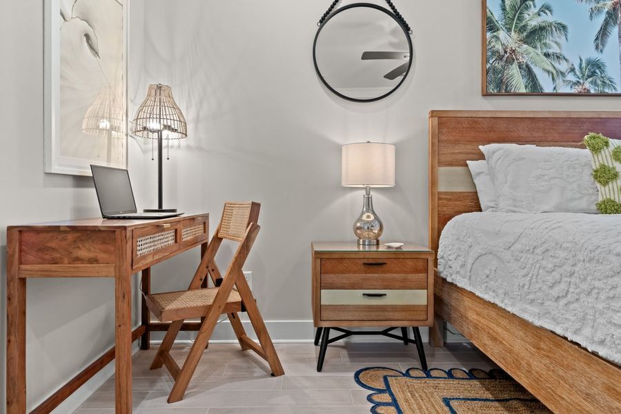 Bedroom with wooden desk and chair, bed with white bedding, and neutral color scheme.
