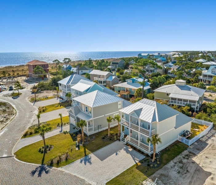 Beachfront houses with light blue exteriors, white trim, and metal roofs.