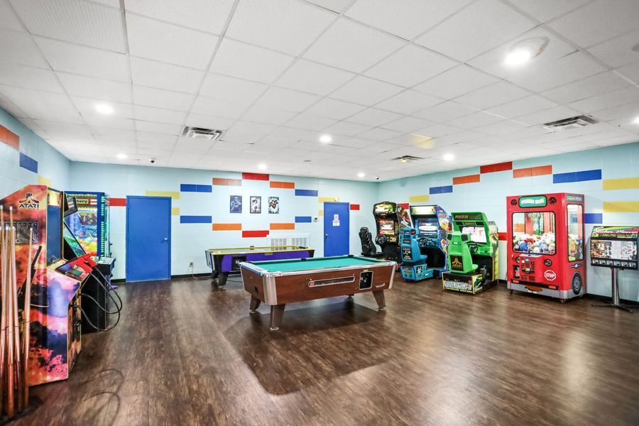 Game room with arcade games, pool table, and colorful wall stripes.
