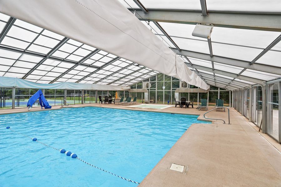 Indoor pool with blue water, a slide, and a translucent roof.