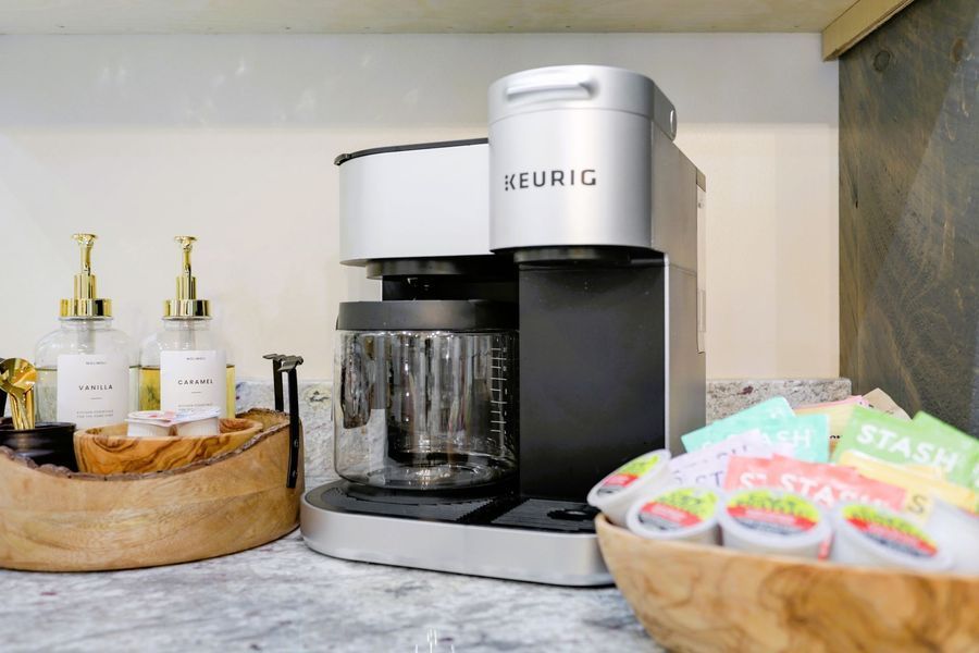 Keurig coffee maker on a countertop with syrup dispensers, K-cups, and tea bags.