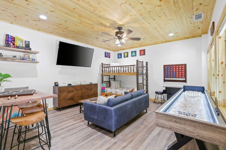 Game room with shuffleboard, bunk beds, TV, and a wooden ceiling.