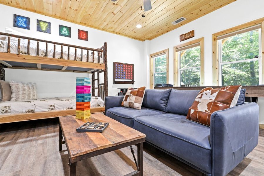 Living room with bunk beds, blue sofa, wooden table, and colorful block tower.