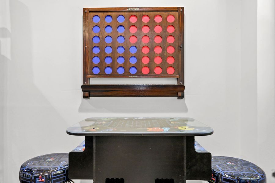 A Connect Four game mounted on a wall above a matching table with stools. Red and blue discs.