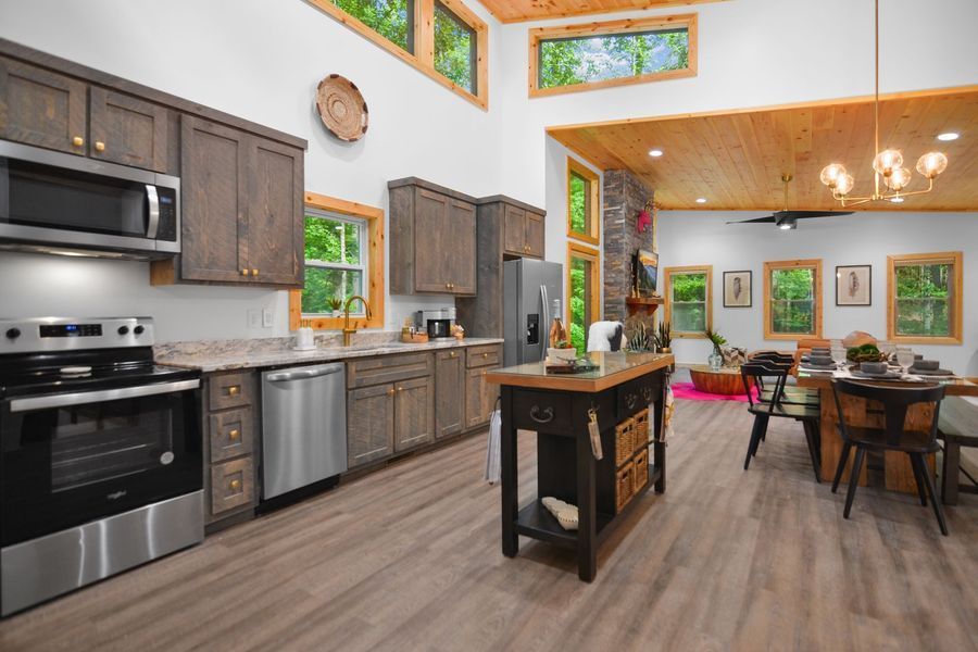 Open-concept kitchen with gray cabinets, stainless steel appliances, and a black island. Dining area with a table and chairs.