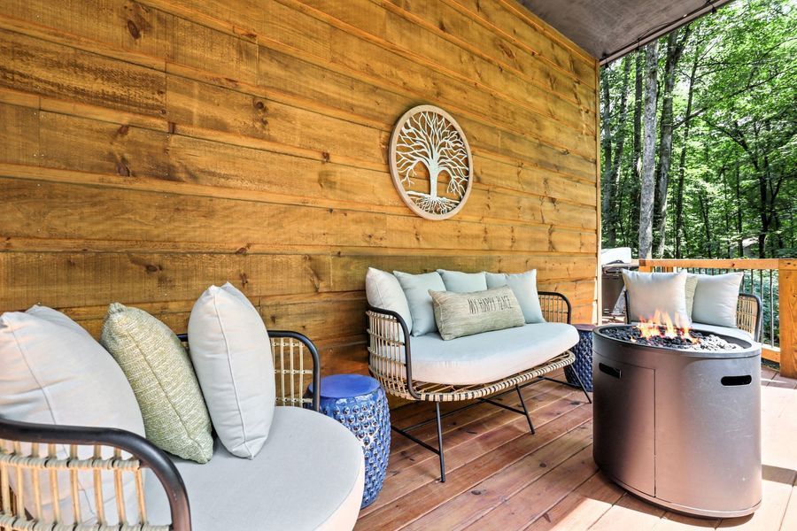 Cozy outdoor seating area with light blue cushions, a fire pit, and a wood-paneled wall with a tree-of-life decor.