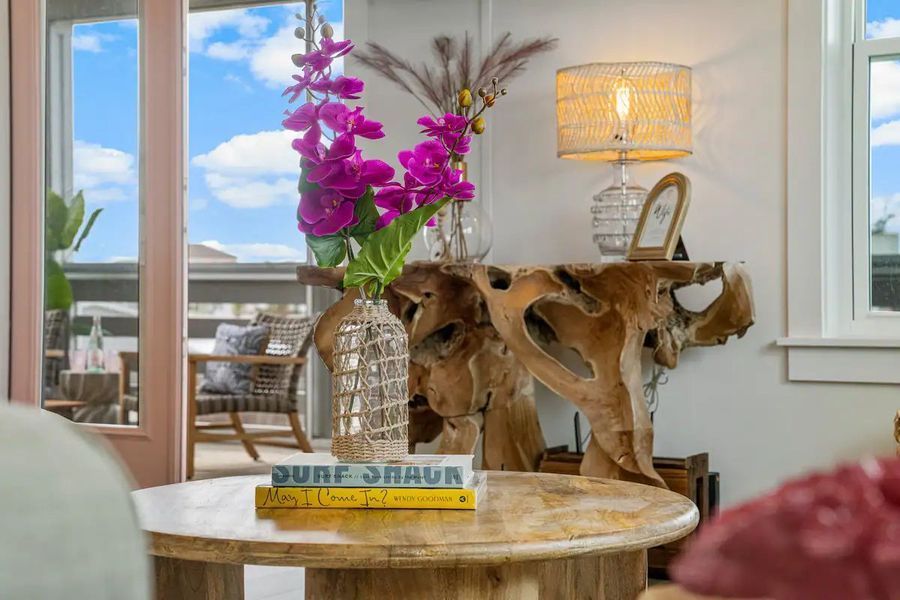 A living room corner featuring a wooden console table, flowers, and a lamp.