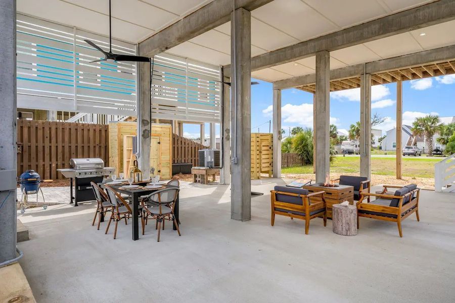Outdoor patio with dining set, seating area, and grill under a house.