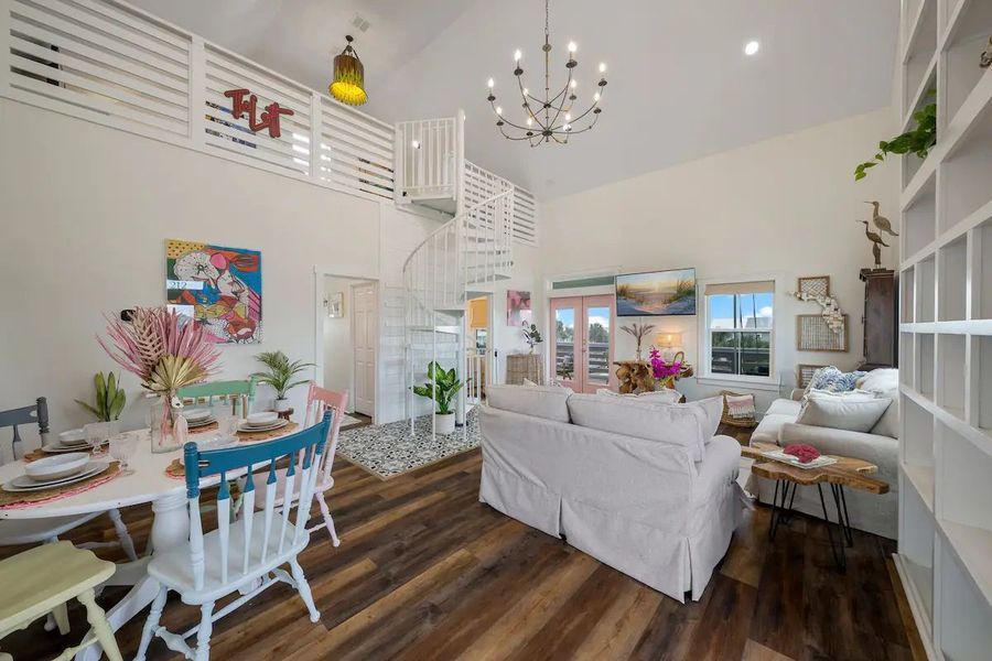 Bright living room with spiral staircase, dining area, and white sofa.