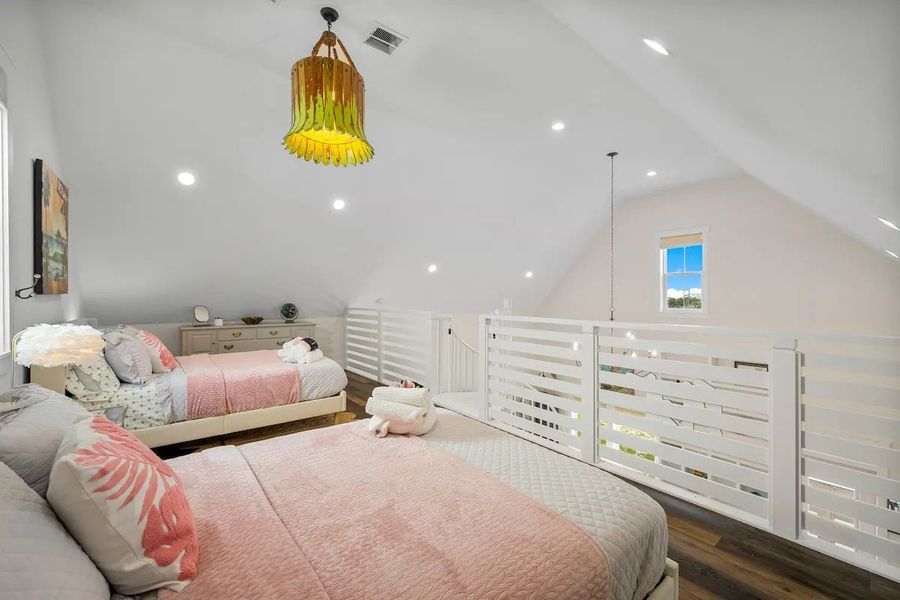 Loft bedroom with two beds, white walls, and a unique yellow light fixture.