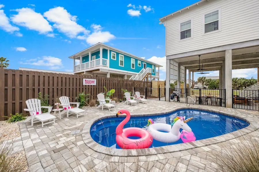 Pool with floats, chairs, and houses on a sunny day.