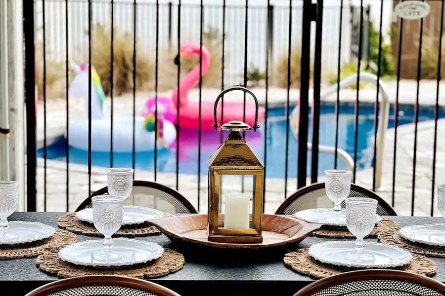 Table set for a meal, pool and flamingo float in the background.