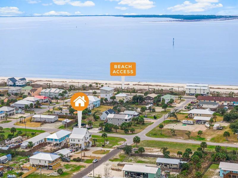 Aerial view of coastal neighborhood with beach access sign and ocean in the background.