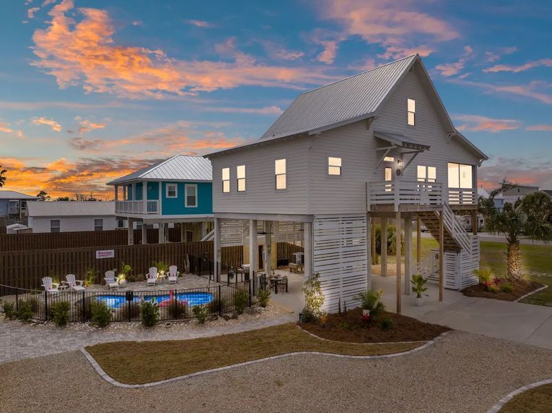 Beach house with pool, white exterior, blue sky at sunset.