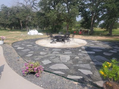 Patio with black stone and gravel surrounding a circular fire pit and seating.