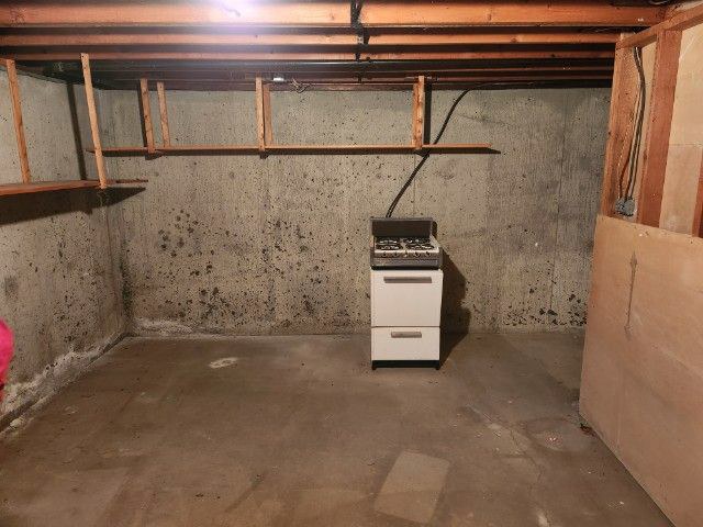 An empty basement with a stove and shelves