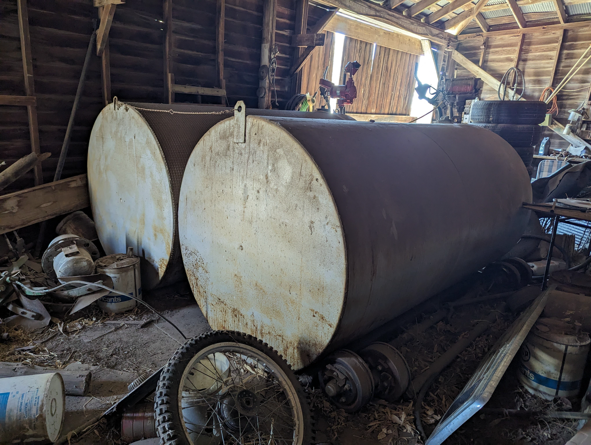 Two large metal tanks are sitting in a wooden barn.