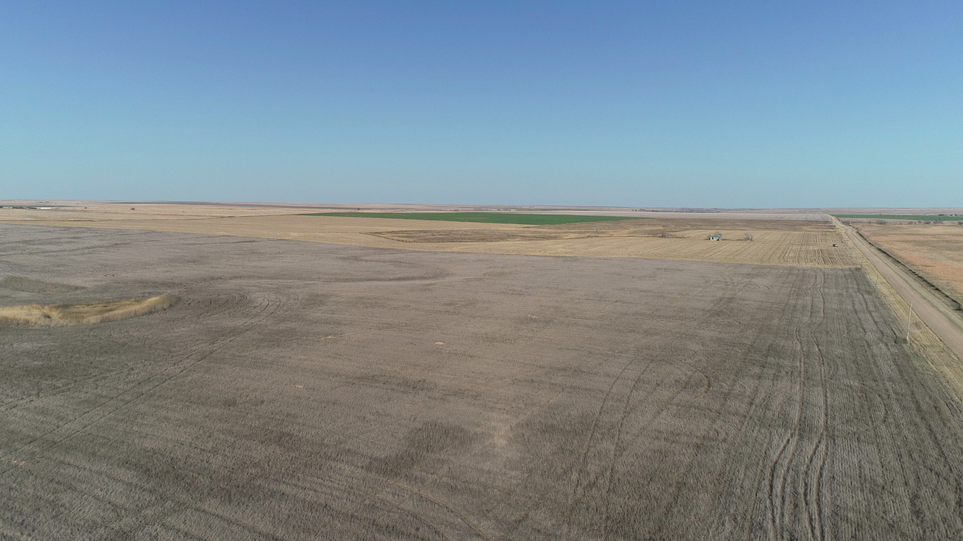 An aerial view of a dry field with a road going through it.