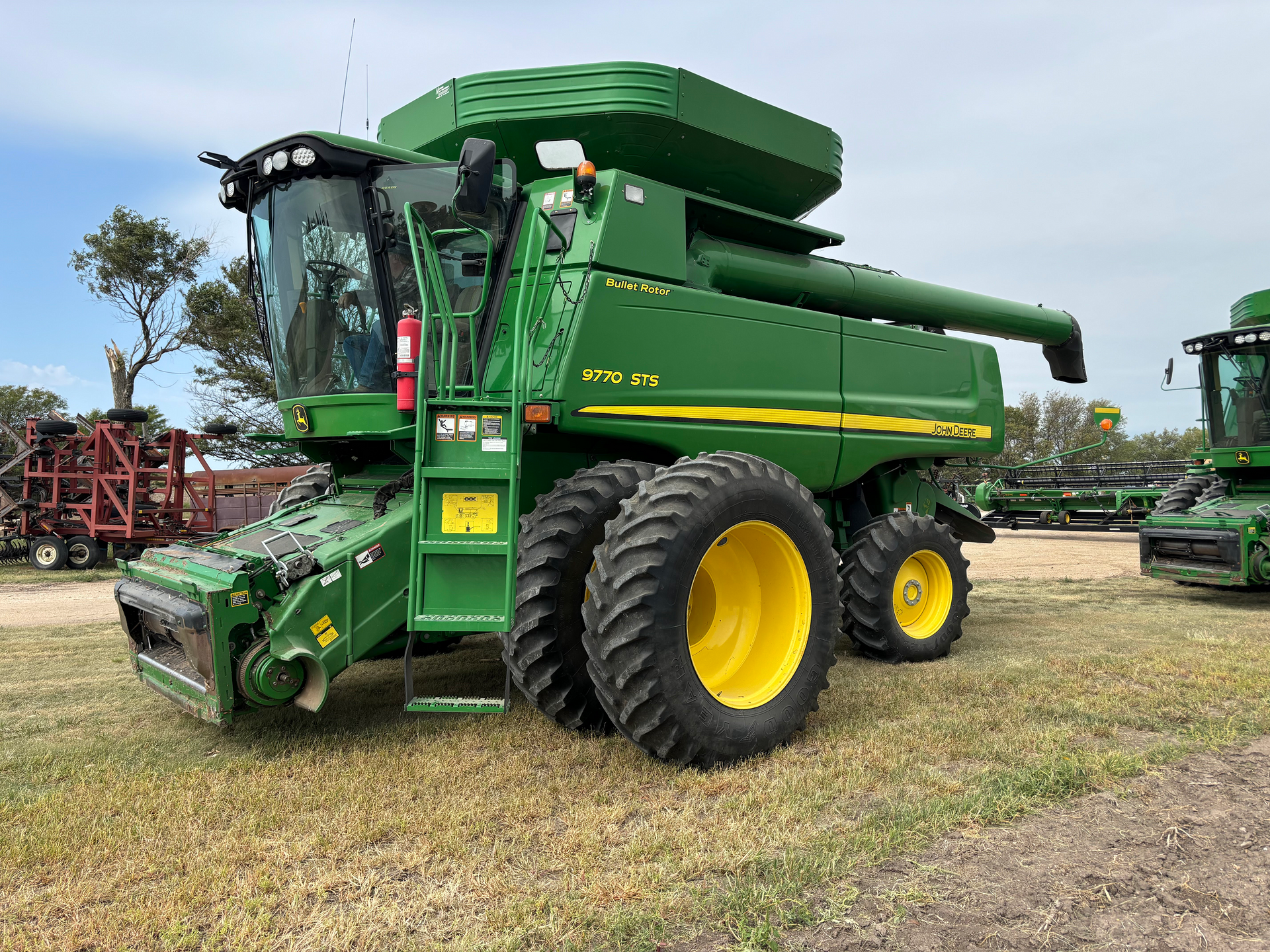 A green john deere tractor with a loader is parked in a grassy field.