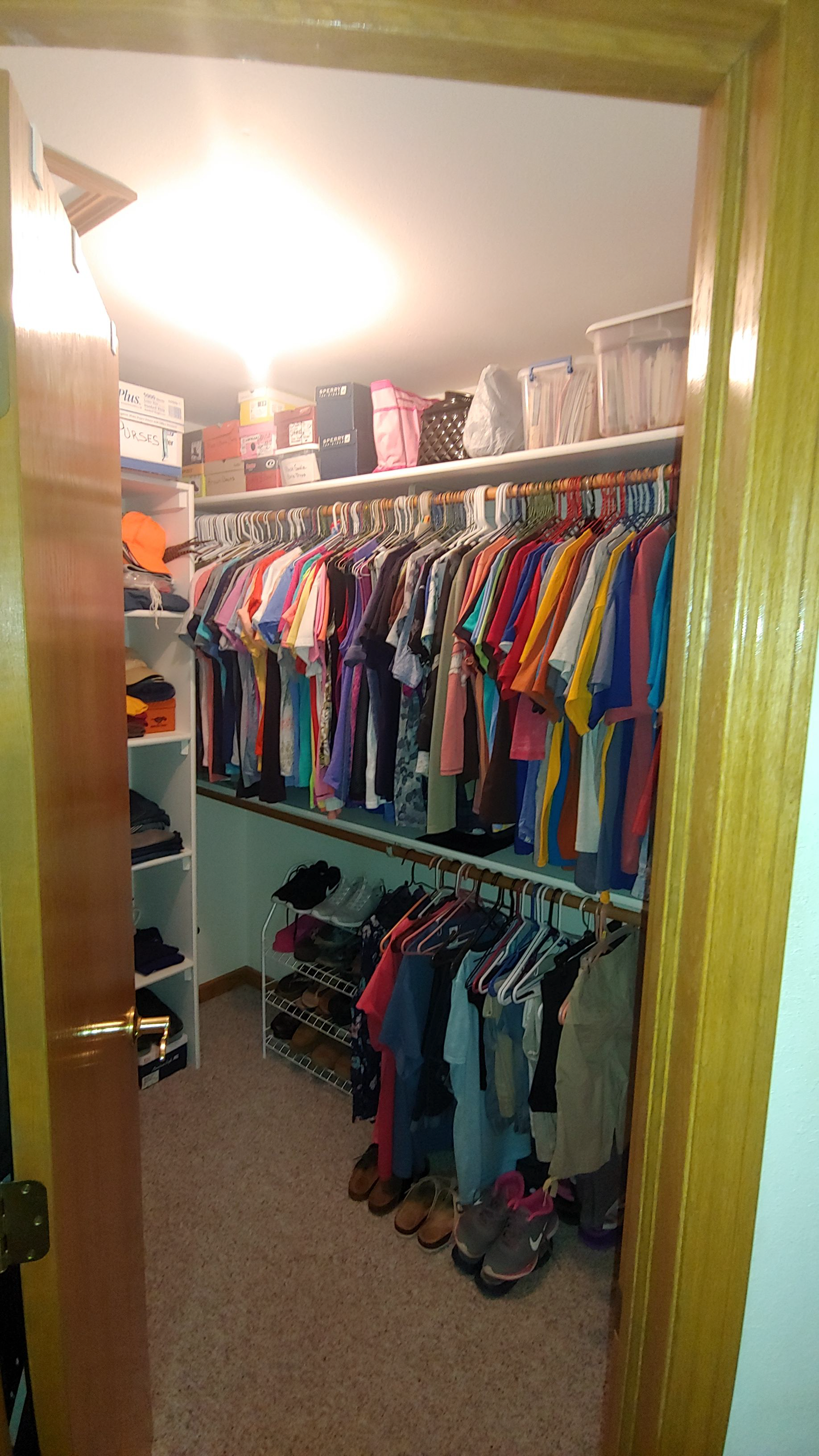 A walk in closet filled with lots of clothes and shoes.