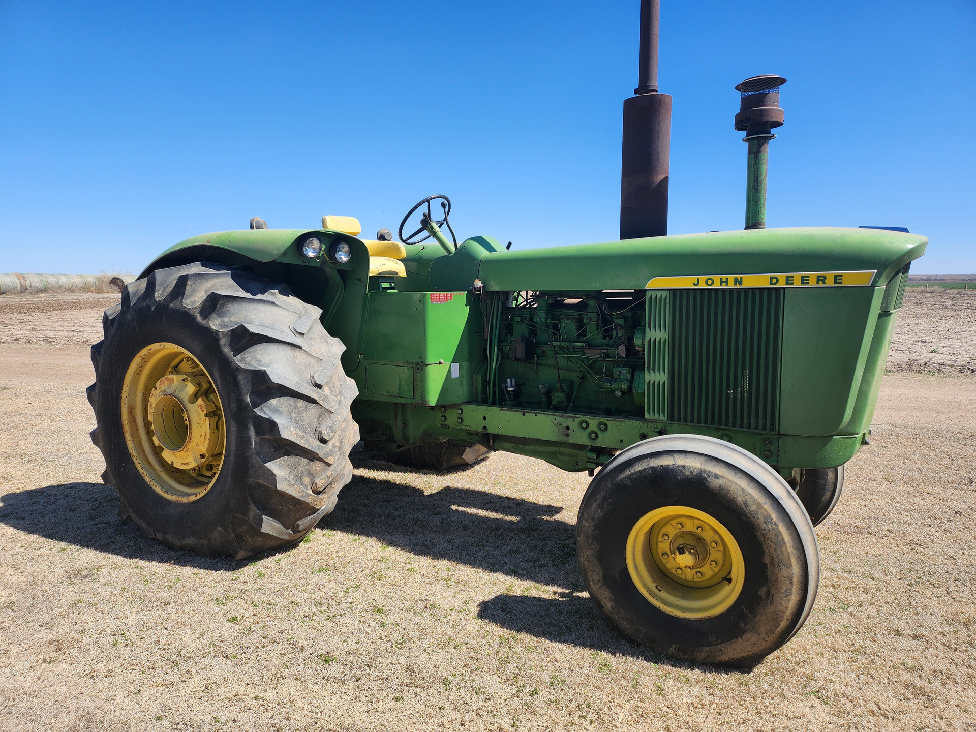 A green and yellow john deere tractor is parked in a field.