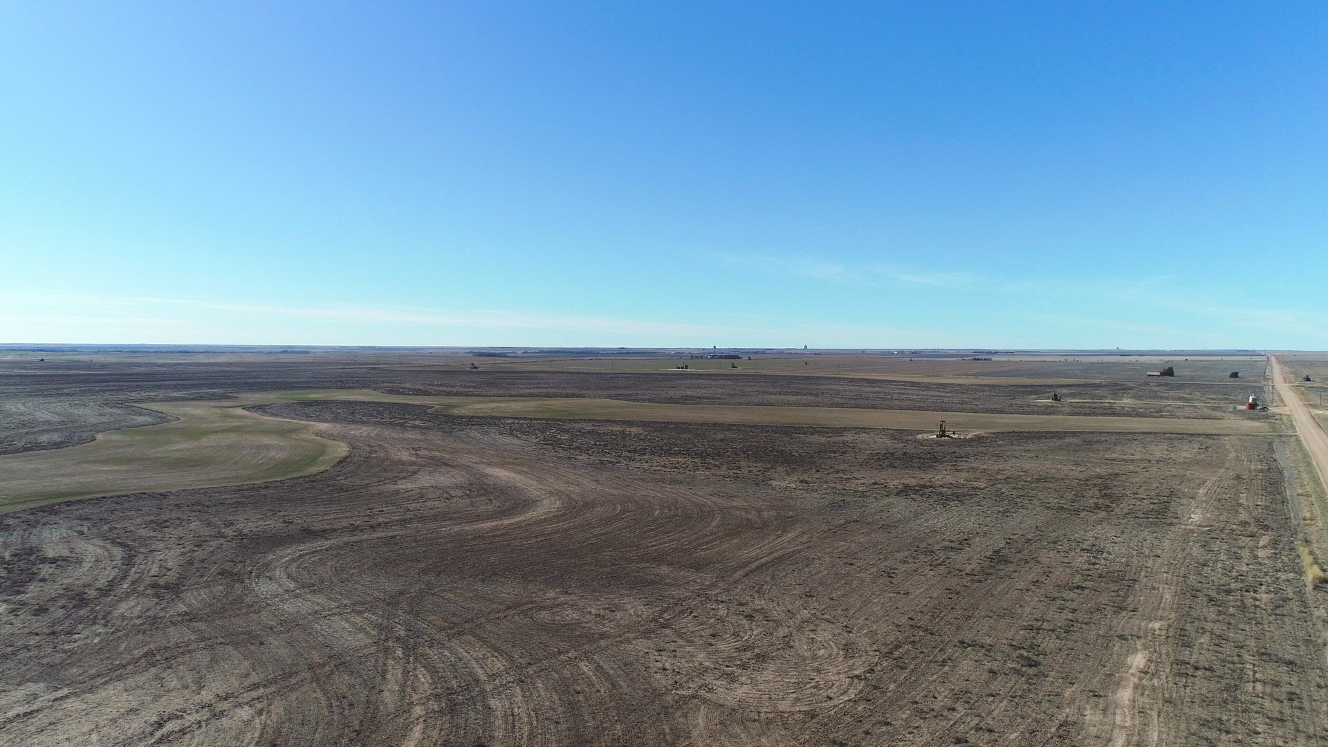 An aerial view of a desert landscape with a dirt road going through it.