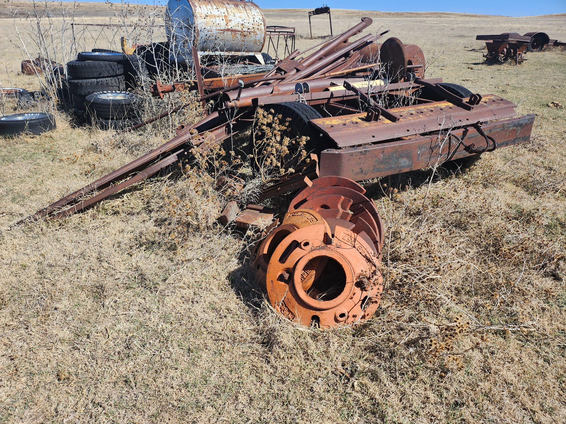 A pile of rusty metal is sitting in the middle of a field.