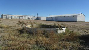 A large white building is sitting in the middle of a field.