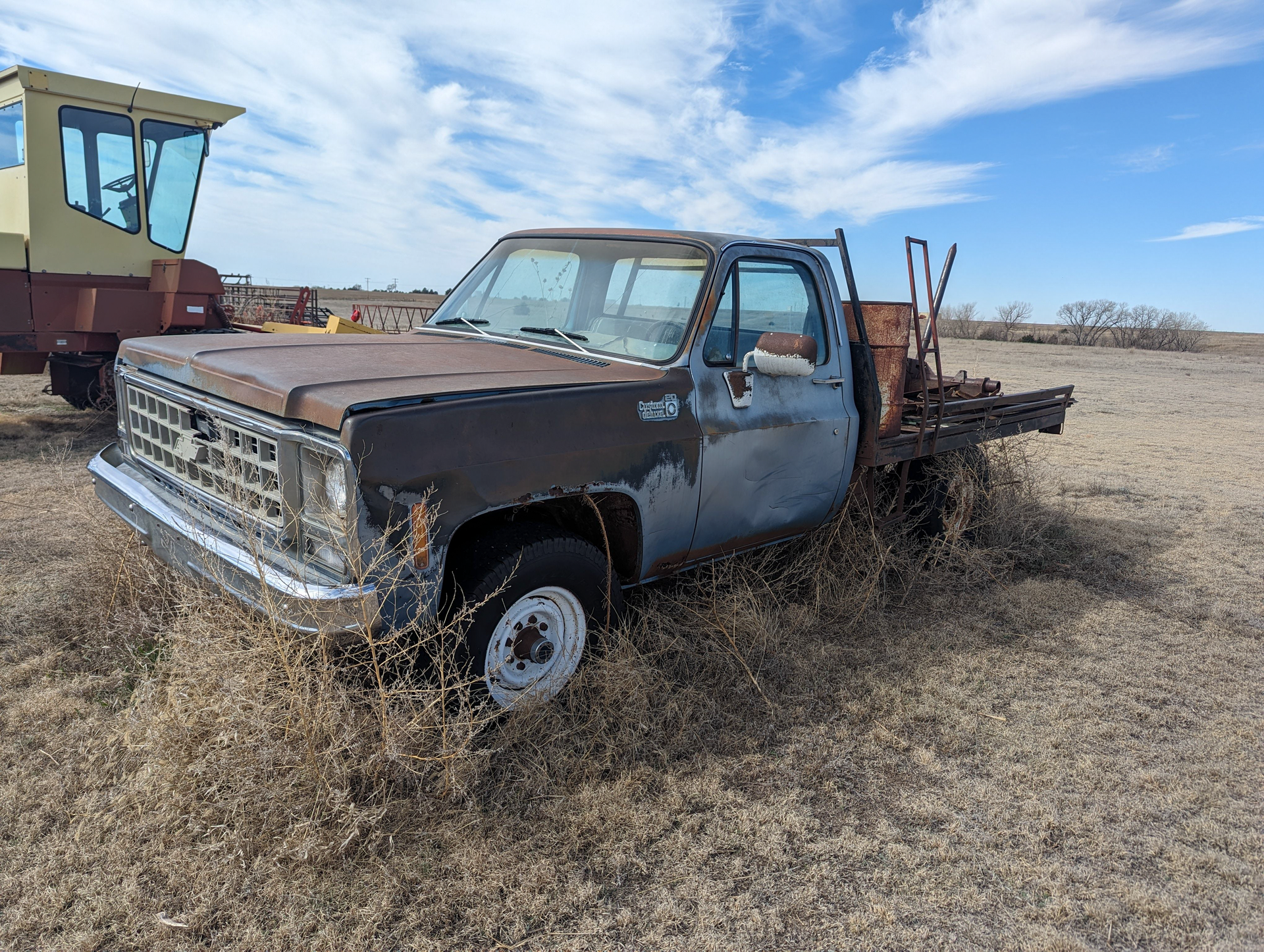 An old truck is sitting in the middle of a field.