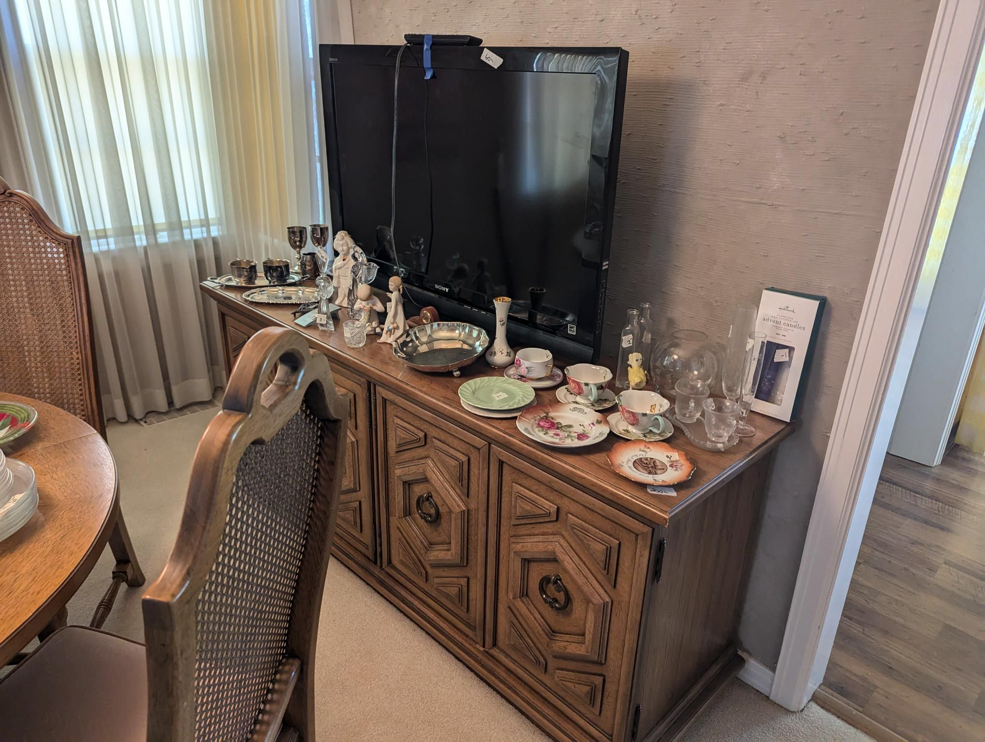 A dining room with a table and chairs and a television on a dresser.