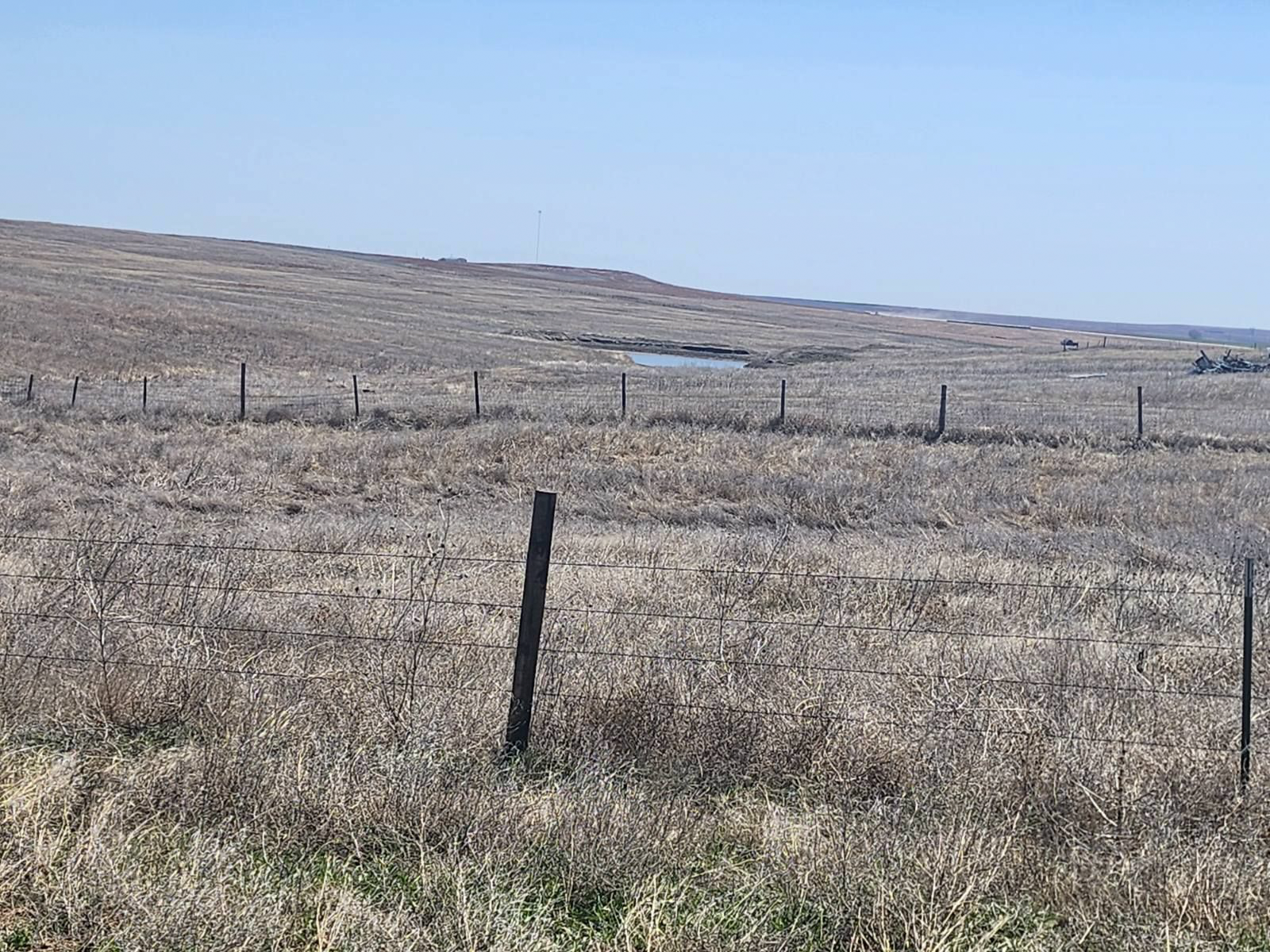 A barbed wire fence surrounds a dry grass field