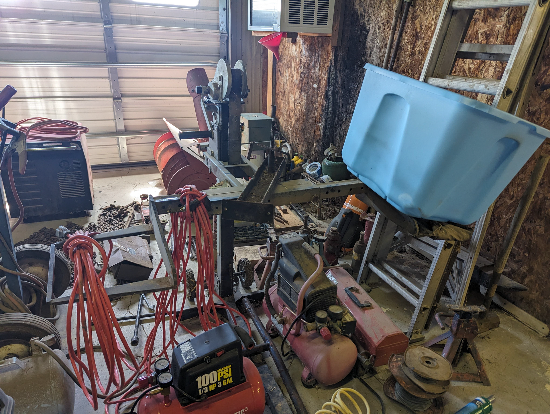 A garage filled with lots of tools and a blue trash can.