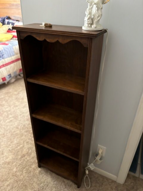 An empty bookshelf in a bedroom with a lamp on top of it