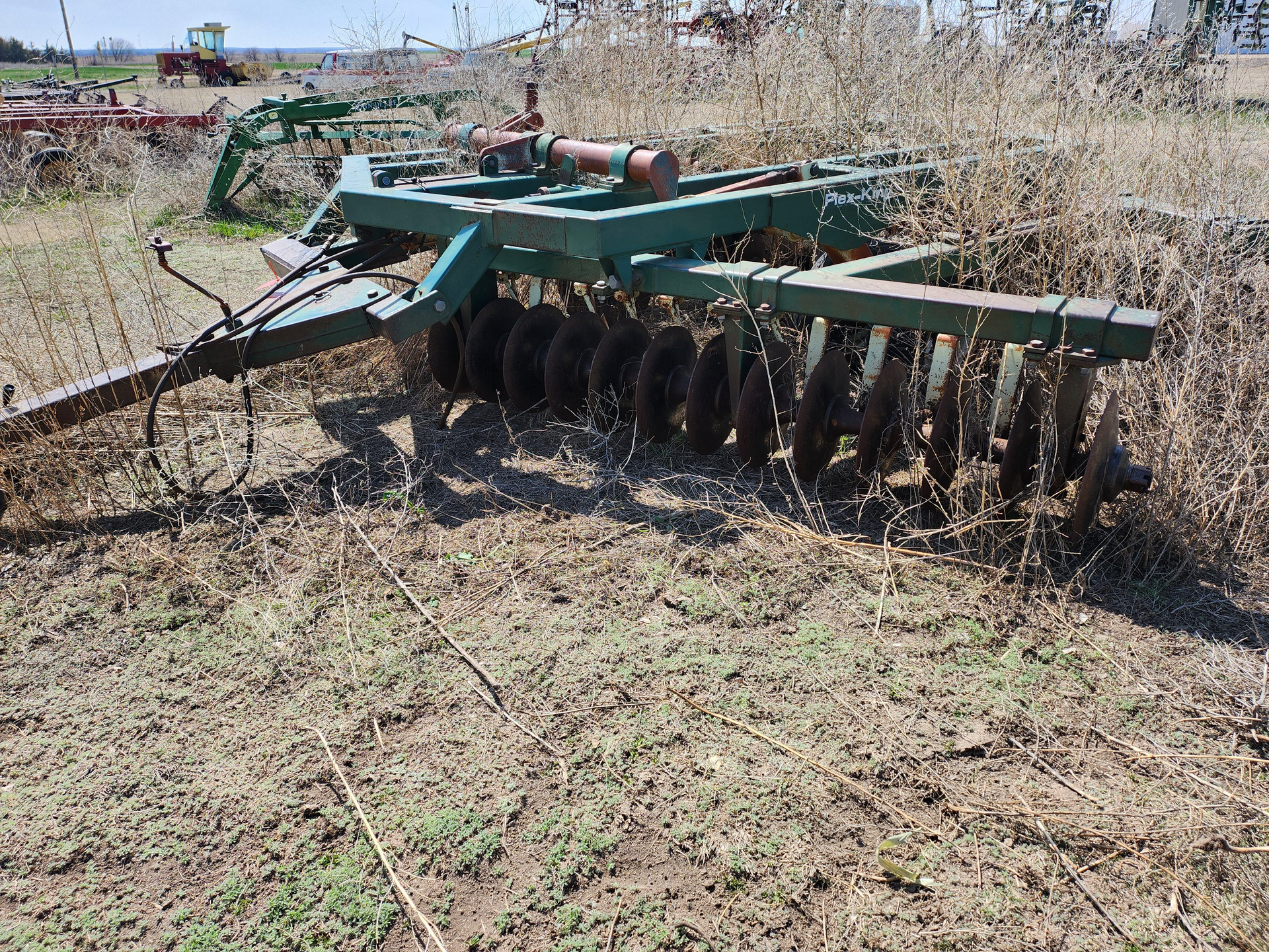 A disc plow is sitting in the middle of a field.