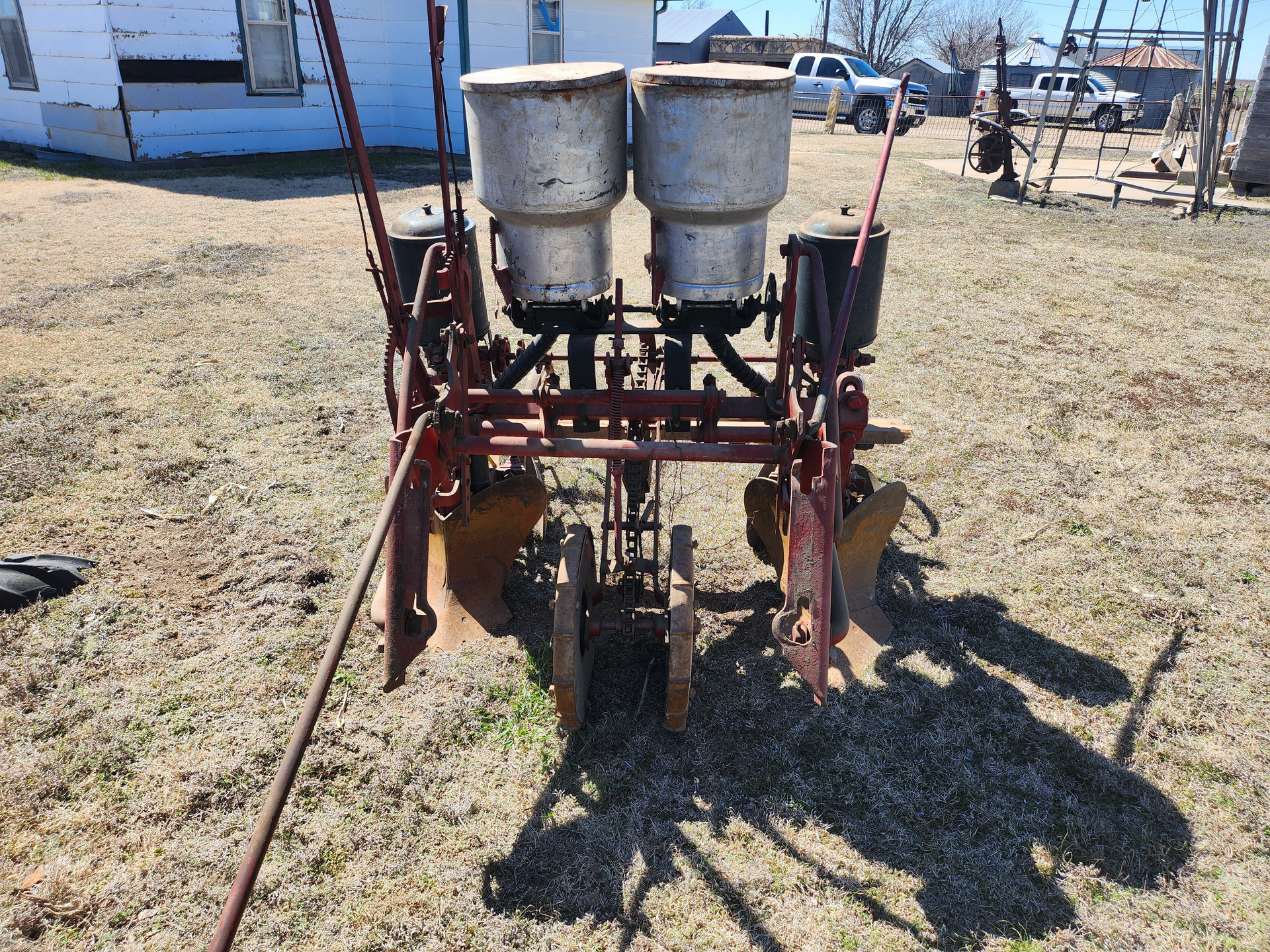 An old planter is sitting in the middle of a field.