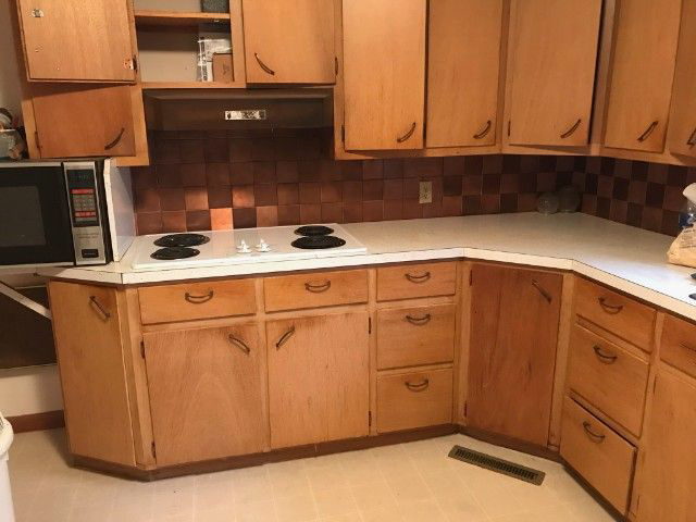 A kitchen with wooden cabinets and a microwave