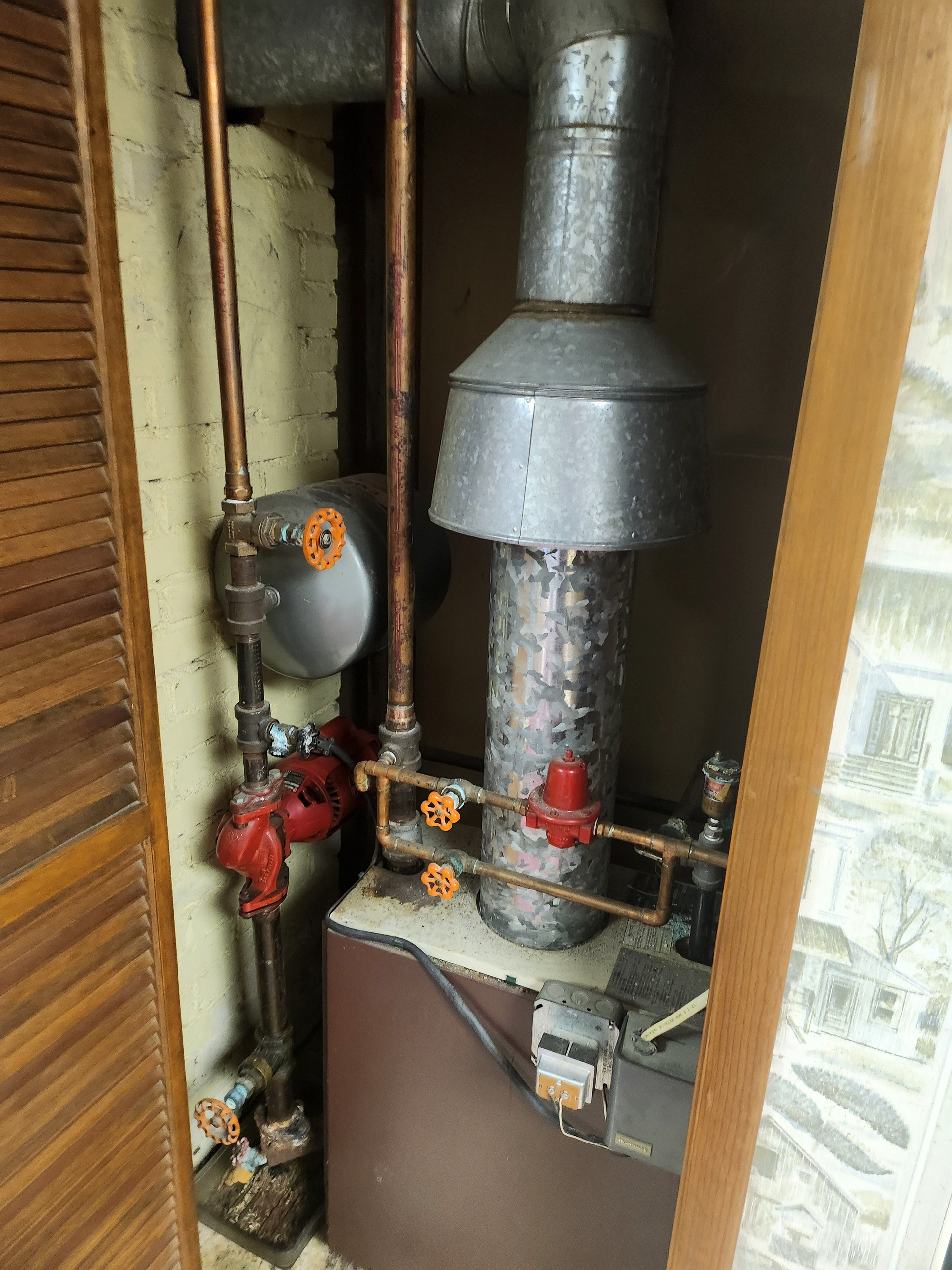 A boiler is sitting in a room next to a door.